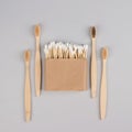 Cotton buds in kraft paper box and natural bamboo toothbrushes on light grey background - zero waste bathroom essentials. Royalty Free Stock Photo