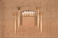 Cotton buds in kraft paper box and natural bamboo toothbrushes on natural burlap background - zero waste bathroom essentials.