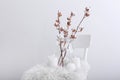 Cotton flowers and burning candles on chair against white background