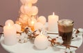 Cotton flowers, burning candles and glass of drink on table