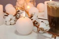 Cotton flowers, burning candles and glass of drink on table, closeup