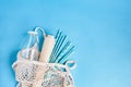 Cotton net bag with reusable glass water bottle, paper and parer colored paper straws. Eco friendly concept. Blue background. Top