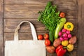 Cotton shopping bag and fresh rustic vegetables on a wooden background. Eco Concept. Copy space. Flat layout.