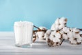 Cotton swabs in clear glass jar in bathroom setting with a cotton flowers on pastel blue background. Copy space. Royalty Free Stock Photo