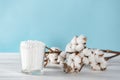 Cotton swabs in clear glass jar in bathroom setting with a cotton flowers on pastel blue background. Copy space. Royalty Free Stock Photo