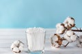 Cotton swabs in clear glass jar in bathroom setting with a cotton flowers on pastel blue background. Copy space. Royalty Free Stock Photo