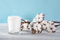 Cotton swabs in clear glass jar in bathroom setting with a cotton flowers on pastel blue background. Copy space. Royalty Free Stock Photo