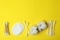 Cotton swabs, pads and flowers on yellow background Royalty Free Stock Photo