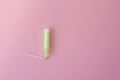 Cotton tampon with light green applicartor on a pink background. Woman days hygiene protection. Menstrual cycle period concept.