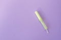 Cotton tampon with light green opened applicartor on violet background. Woman days hygiene protection. Menstrual cycle period