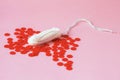 Cotton tampon and red beads as blood drops isolated on pink background