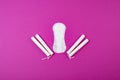 Cotton tampons with an applicator and sanitary pads on a pink background