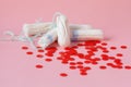 cotton tampons and red beads as blood drops isolated on pink background