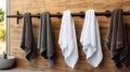 Cotton terry towels in white, black, and grey hanging on a rail in an empty space. Generative AI