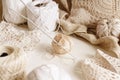 Cotton thread and hook on a table surrounded by cotton balls and doilies