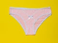 Cotton women`s pink panties on a bright yellow background close-up. Beautiful lingerie. The view from the top