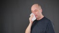 Coughing man blowing nose in paper napkin on black background. Cold man sneezing and blowing nose while influenza