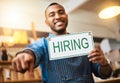 This could be the perfect position for you. Portrait of a young man pointing while holding up a hiring sign in his store Royalty Free Stock Photo