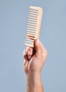 This could untangle the Gordian knot. an unrecognizable man holding a comb against a blue background.