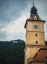 The council house clock tower with a beautiful view to the Brasov sign on top of the hill. Popular tourist location in Romania Royalty Free Stock Photo