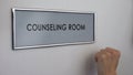 Counseling room door, hand knocking closeup, family therapy, support group
