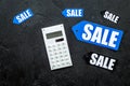 Count the benefits from the sale. Word sale on label near calculator on black background top view copyspace Royalty Free Stock Photo