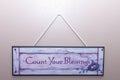 Count your blessings sign hangs on the wall in a home to remember thankfulness and remembering blessings in life
