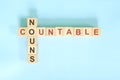 Countable nouns concept in English grammar noun education. Wooden block crossword puzzle flat lay in blue background.