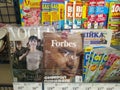 A counter in a store with newspapers and periodicals. VOGUE, Forbes and other magazines.