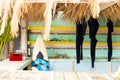 Counter of sunny surf hire shop on beach with radio, surfboard and hanging wetsuits