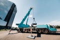 The counterweight is installed by an unrecognizable worker on a large blue car crane and is prepared to work on a site next to a