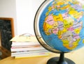 Countries and continents close up with the color map on a globe with books in the background.