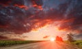 Country asphalt road leaving on dramatic bright sunset sky