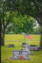 Country cemetery with religious tombstones and flowers and an American flag between two trees with Royalty Free Stock Photo