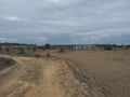 Country dirt road through bare field with abandoned ruined blue house and dry trees near Odeceixe, Portugal. Cloudy Royalty Free Stock Photo