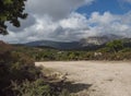 country dirt road at landscape of Supramonte Mountains with green hills, trees and mediterranean forest vegetation Royalty Free Stock Photo