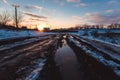 Country dirt road with muddy puddles and melting snow in early spring at sunset Royalty Free Stock Photo