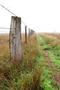 Country fence near a dirt road on a foggy morning