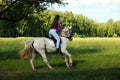 Counrty girl riding horseback on a meadow against woods Royalty Free Stock Photo