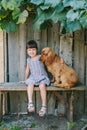 Country girl sitting on a bench with her dog under vine. wooden Royalty Free Stock Photo