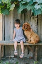 Country girl sitting on a bench with her dog under vine. wooden Royalty Free Stock Photo