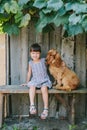 Country girl sitting on a bench with her dog under vine. wooden Royalty Free Stock Photo