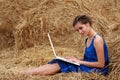 Country girl sitting on hay with laptop Royalty Free Stock Photo