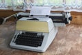 In a country house with wooden walls and transparent curtains, a typewriter stands on an old wooden table