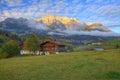 Country houses at foothills of a rocky mountain range illuminated by golden sunlight at sunset