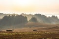 Country landscape. Colorful sunrise in foggy countryside over agricultural field with harvested wheat Royalty Free Stock Photo