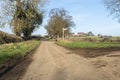 Country lane in winter with blue sky, trees, barn, houses and signpost Royalty Free Stock Photo