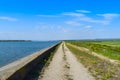 Country road along the lake dam in a sunny summer day with perfect blue sky Royalty Free Stock Photo