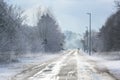 Country road with bushes and bare trees in winter  slippery and dangerous for traffic due to wetness  mist  snow and ice  two Royalty Free Stock Photo