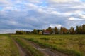 Country road in the field leading to the village, golden autumn in the Russian outback, Kostroma Region